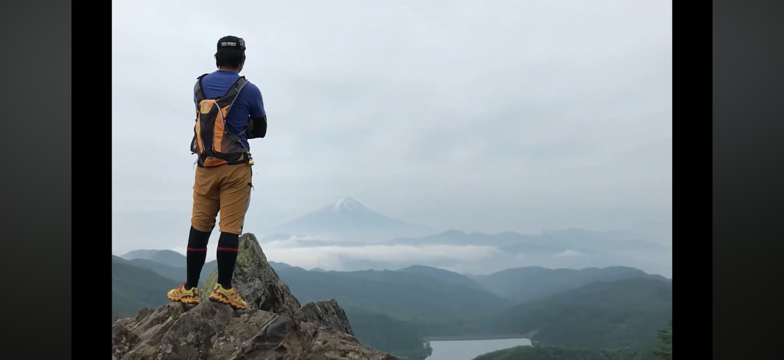 大菩薩の岩場から富士山と大菩薩湖を眺める登山者