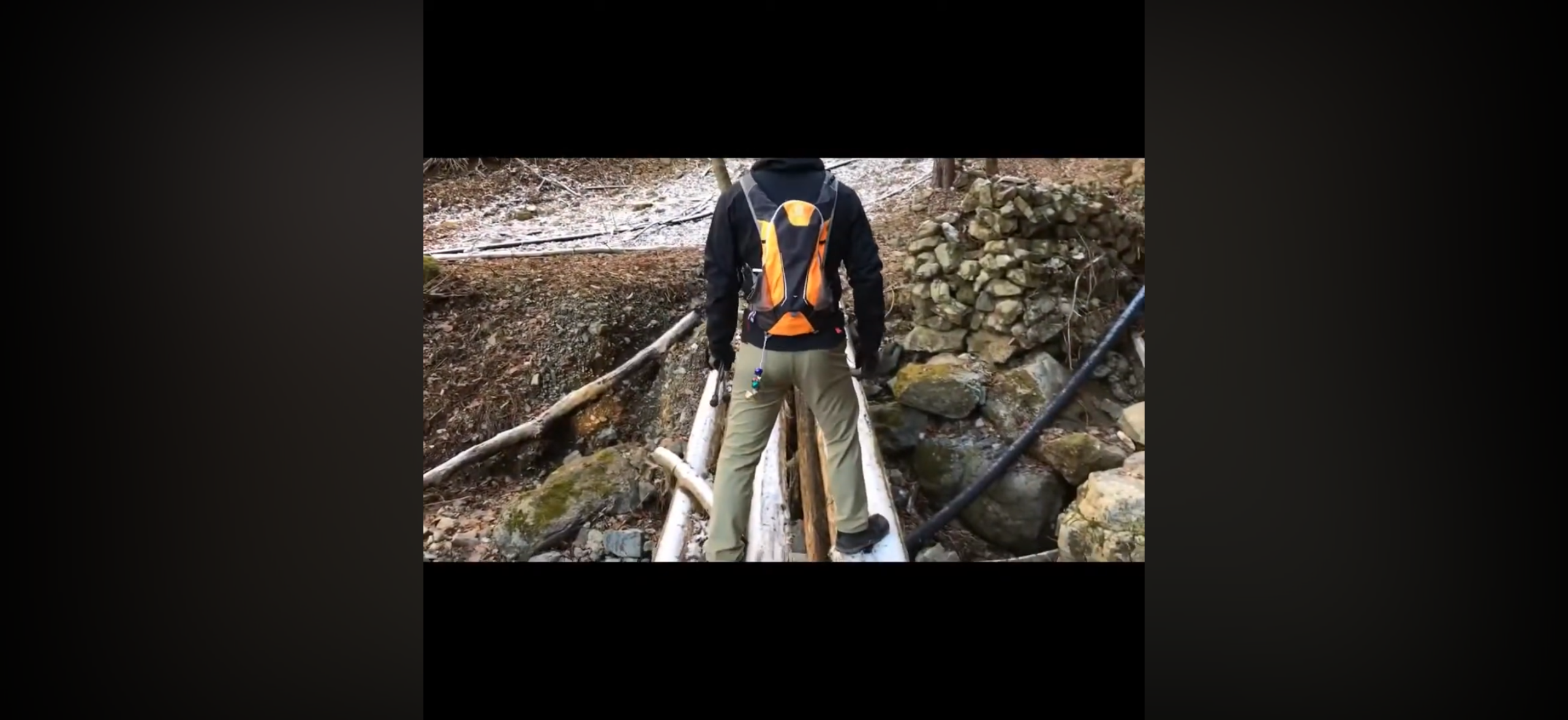 雪が残る三方分山の登山道で丸太を組んだ橋を渡る登山者の後ろ姿